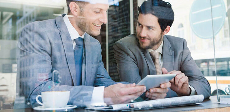 Twee zakenmannen praten en kijken op tablet